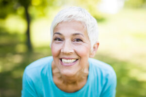 Portrait of a smiling sporty senior woman in a park at summer day