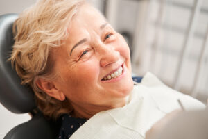 Perfect smile. Calm happy senior female patient sitting at the dentist chair and smiling after the treatment. Pensioner woman visiting stomatology cabinet concept. Stock photo