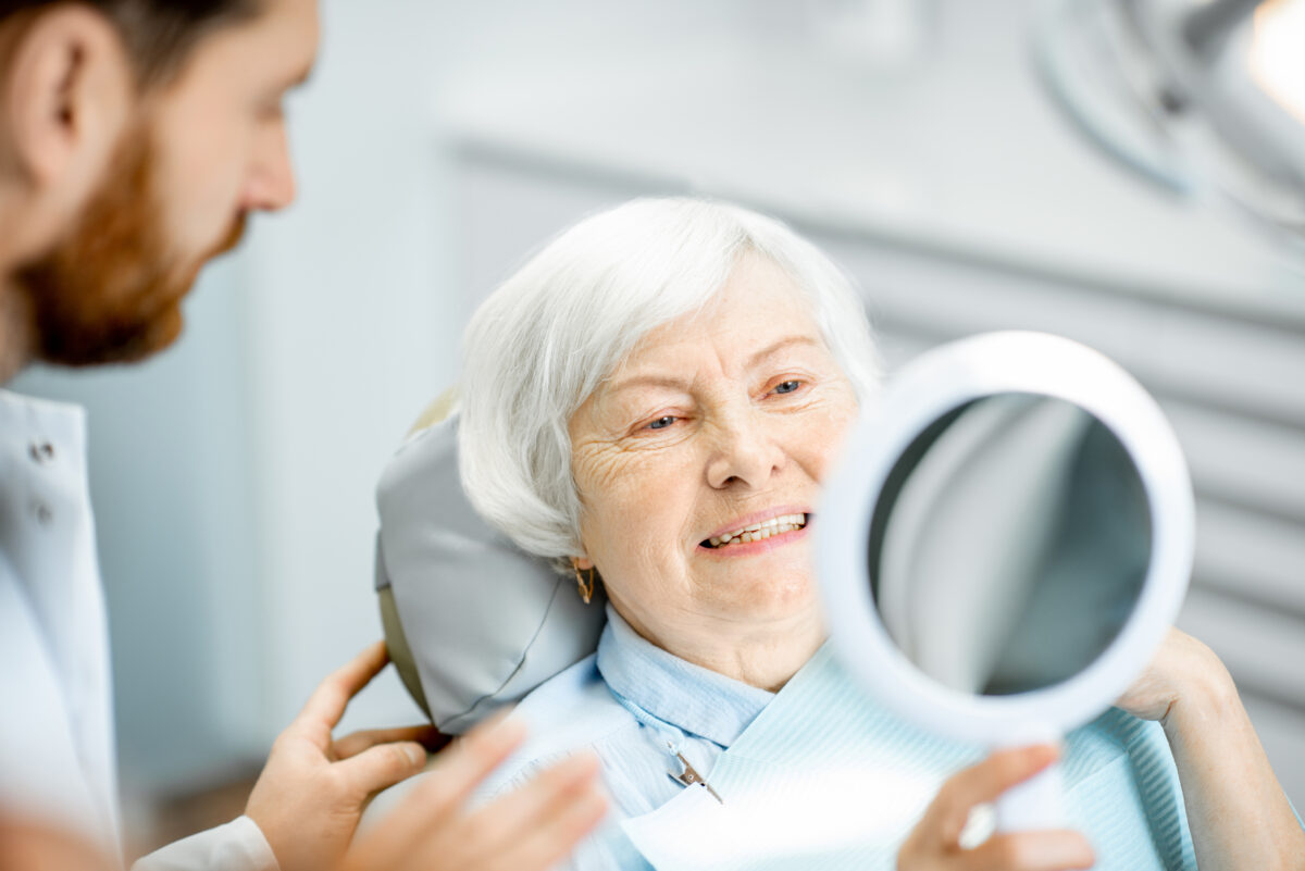 Happy senior woman smiling in the dental office mirror