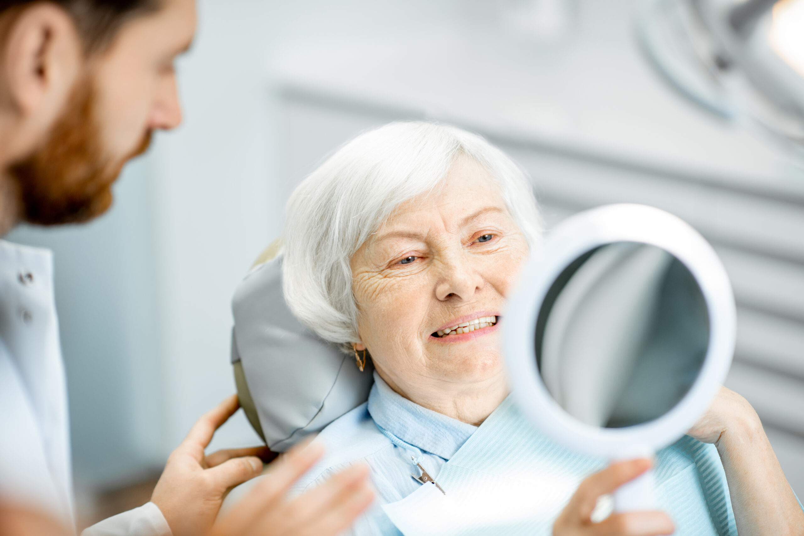 Happy senior woman smiling in the dental office mirror