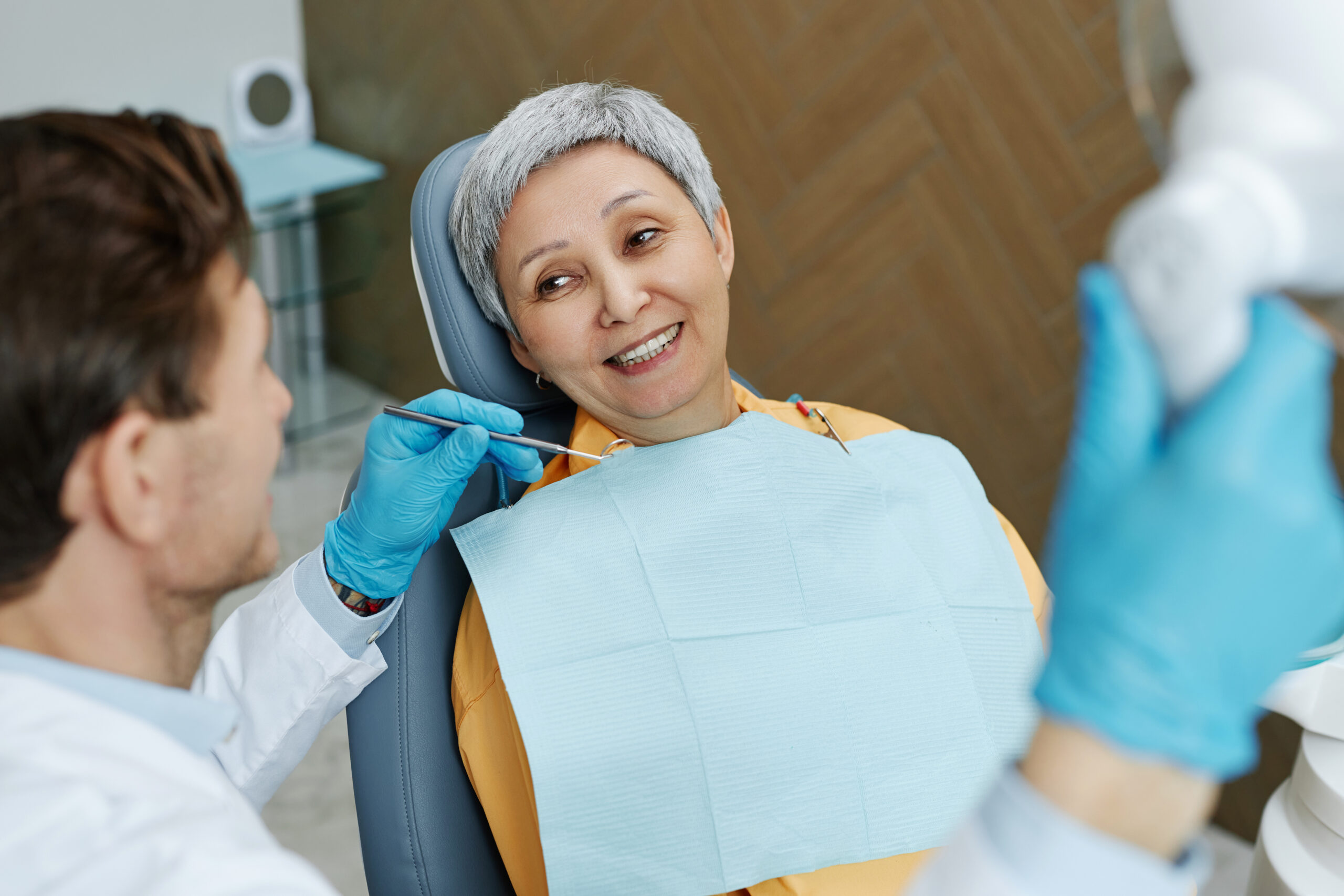 Smiling senior woman in dental chair talking with her dentist