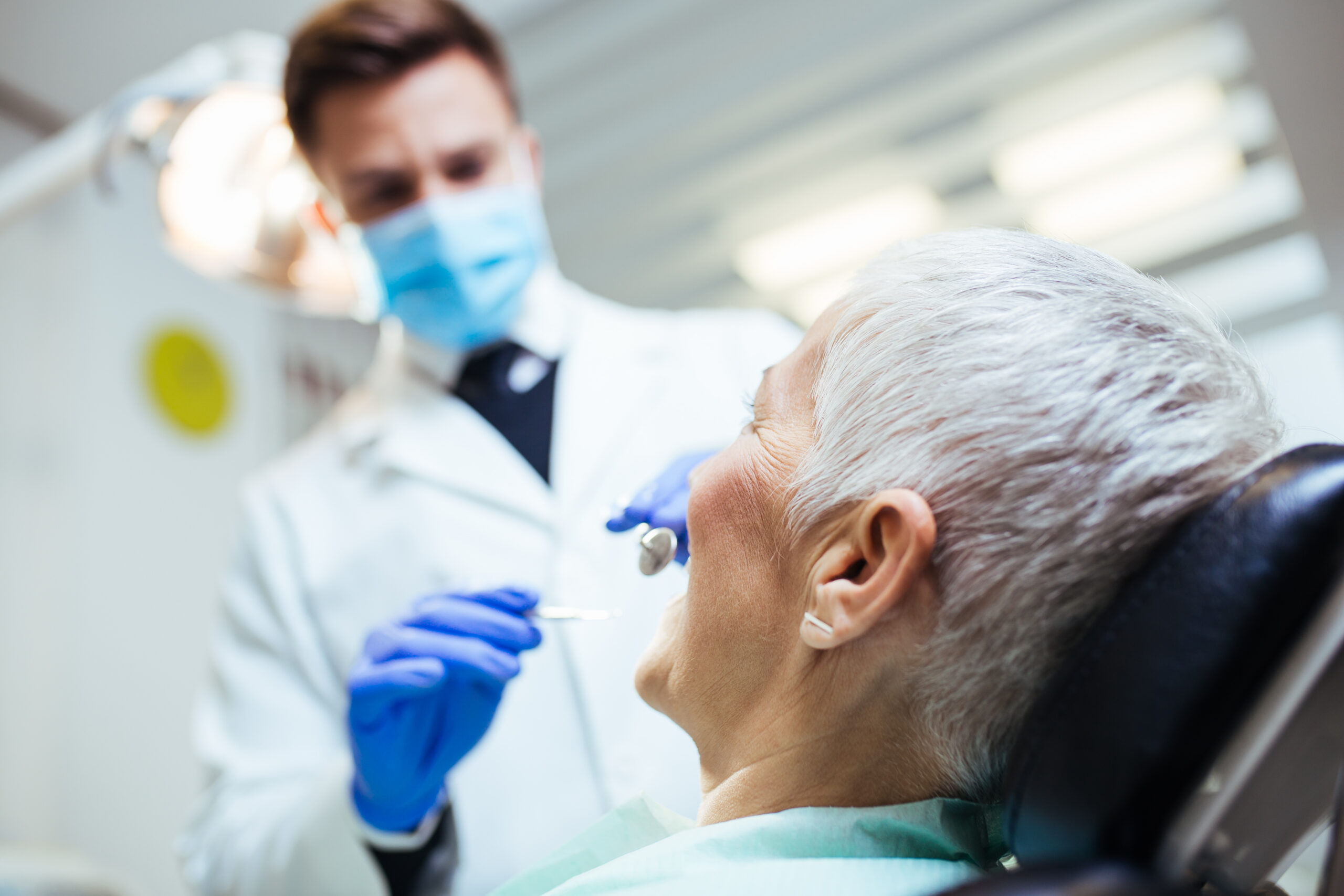 Senior woman smiling confidently after receiving snap-in dentures at a dental office