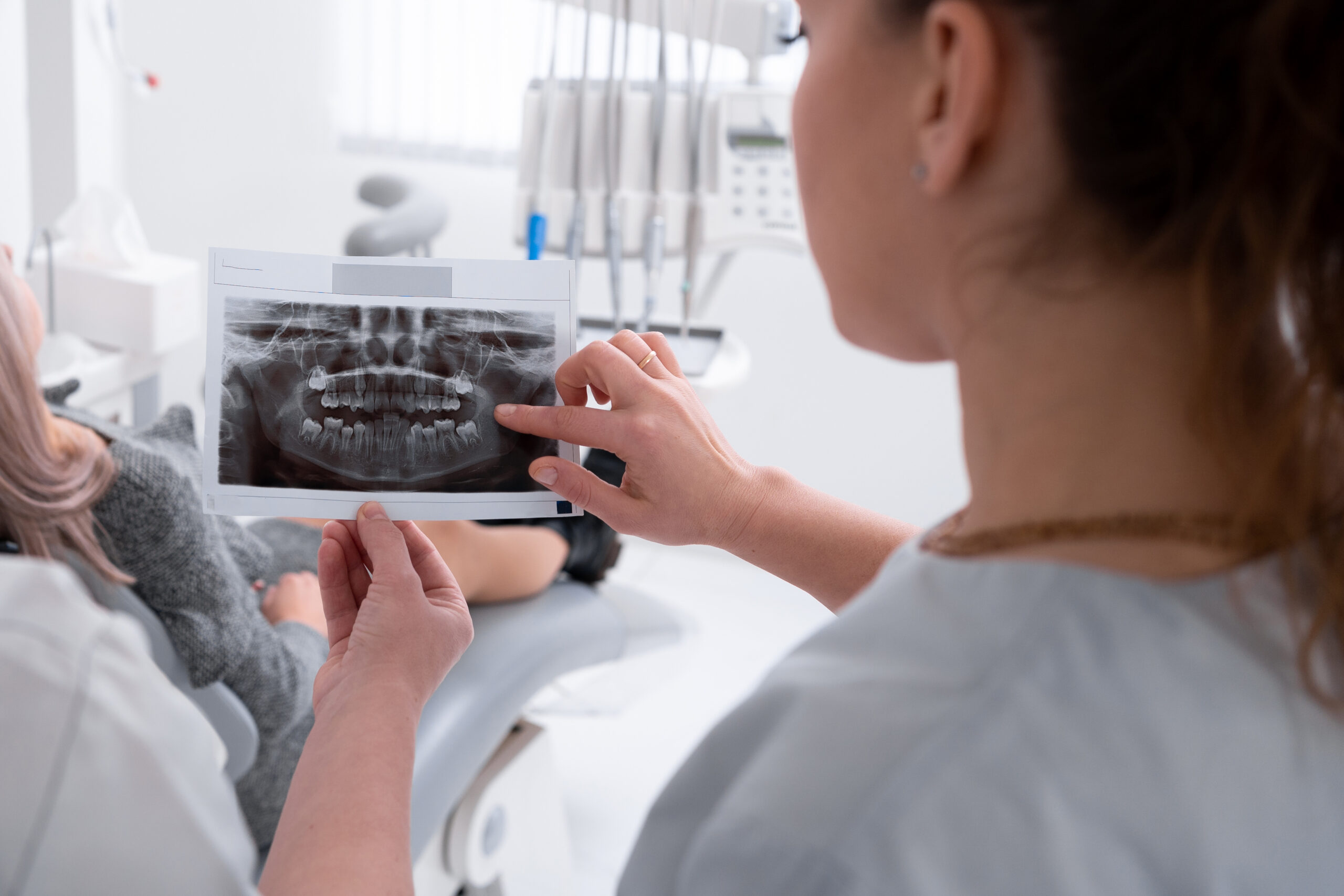 Dentist examining a patient's jaw and teeth, discussing TMJ and bite-related jaw pain